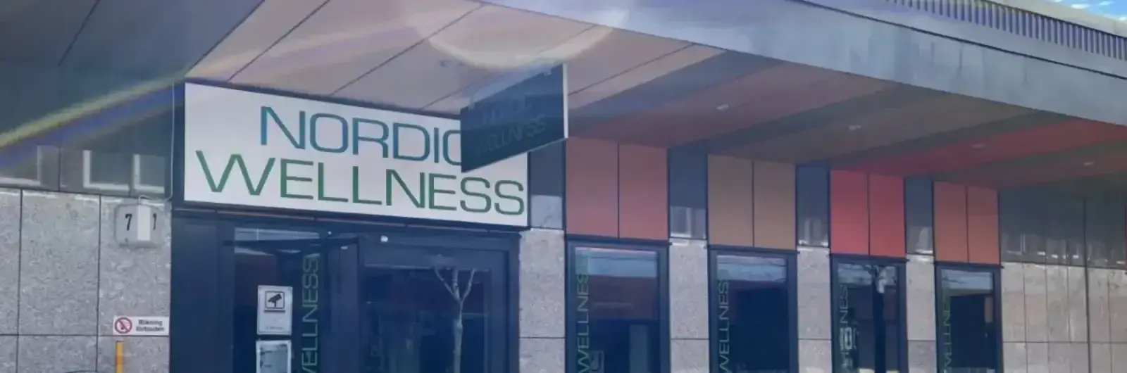 Takarbete på Nordic Wellness-lokal, kvällsbild med belyst skylt