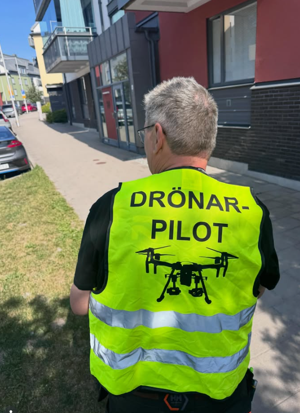 Drönarpilot i varselväst vid takbesiktning av flerbostadshus
